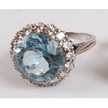 A white metal, aquamarine and diamond circular cluster ring, the centre round faceted aquamarine