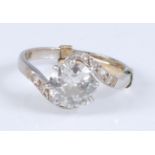 A white metal single stone diamond crossover ring, the round brilliant cut diamond in an eight