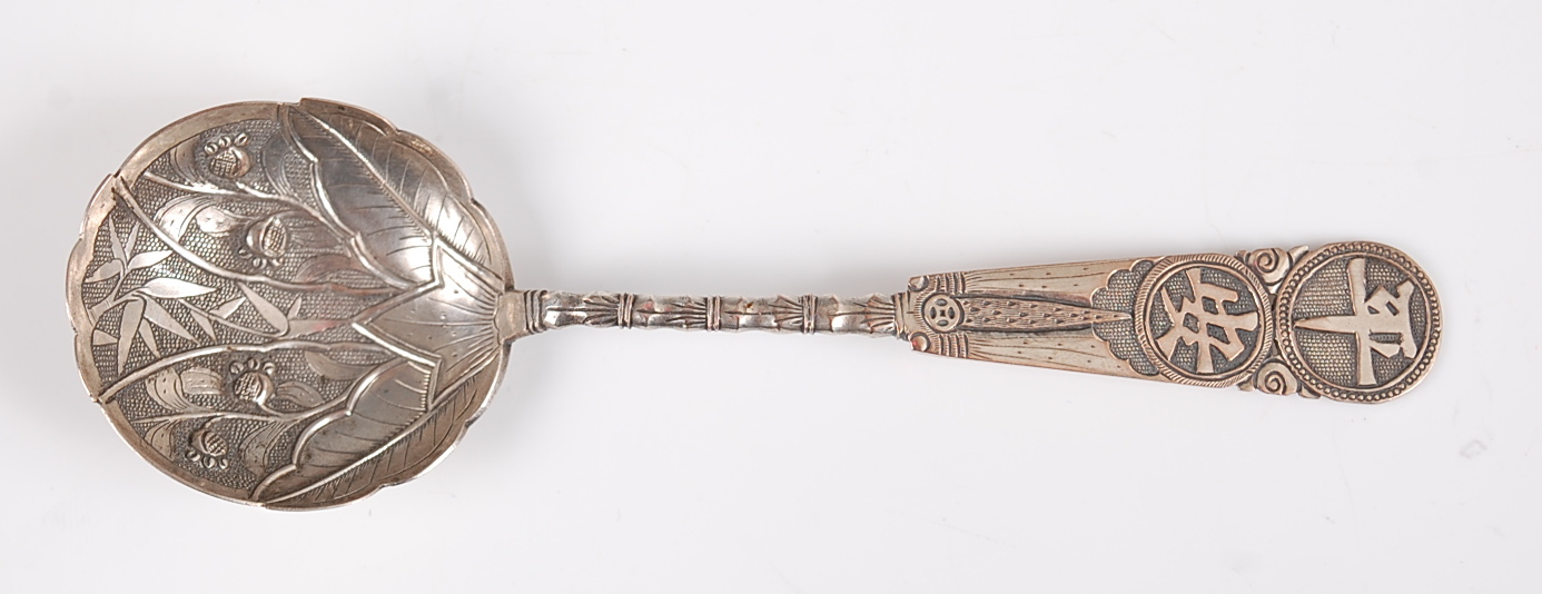 A Japanese Meiji period white metal spoon, the bowl decorated with leaves and bamboo, the stem