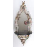 A 19th century German porcelain wall mirror, probably by Meissen, the shaped plate in a C-scroll