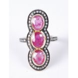 A yellow metal, ruby and diamond vertical triple cluster ring, the three graduated oval rubies