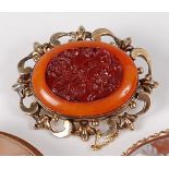 A 19th century yellow metal, carved agate and amber set brooch, the central red agate panel