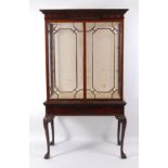 A circa 1900 mahogany cabinet on stand, in the mid-18th century style, having a carved frieze over