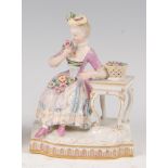 A late 19th century Meissen porcelain figure, modelled as a lady sat at her dressing stool beside