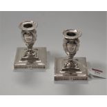 A pair of Adam style silver plated dwarf candle sticks, decorated with rams heads and swags, on a