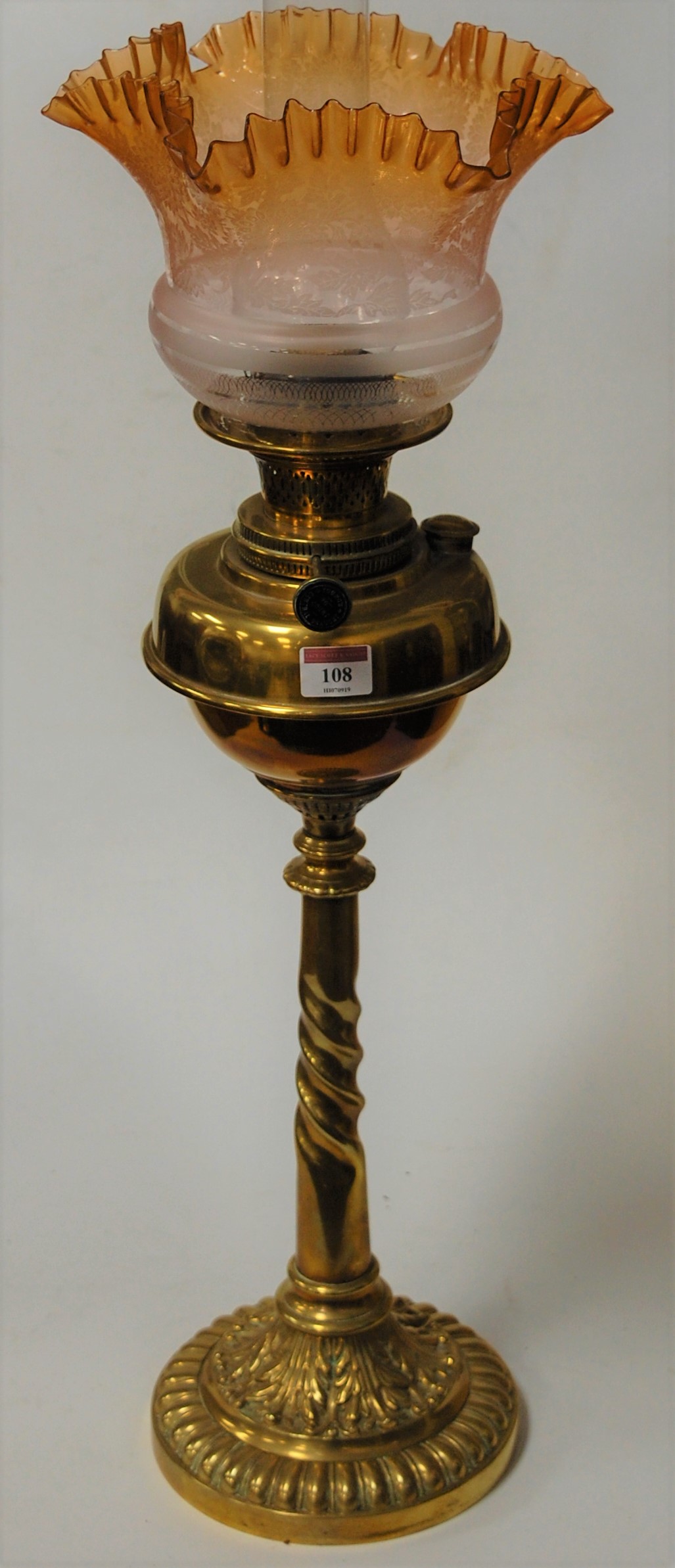 A late Victorian pedestal oil lamp, having an amber tinted and acid etched glass shade over a