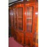 A contemporary mahogany serpentine front display cabinet, having four glazed upper doors enclosing