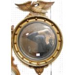 A Regency style giltwood circular wall mirror, having eagle surmount and ball decorated inner