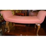 An early 20th century beech framed and pink upholstered twin window seat, having winged arm rests
