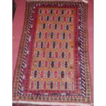 A small Persian red ground woollen rug, having a geometric central ground within trailing borders,