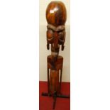 A carved and stained Easter Island style hardwood figure, raised on later black painted wrought iron