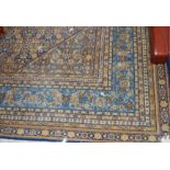 A large Persian style machine-woven blue ground rug, having a heavy floral ground within trailing