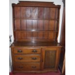 An early 20th century oak dresser, having two-tier open plate rack and panelled back, the base