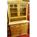 A pine round cornered dresser, having twin door glazed upper section over base with twin frieze