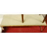 A contemporary Giacometti style gilt metal long bench stool, having fixed upholstered drop-in