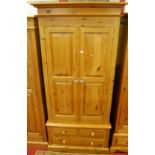 A modern pine twin panelled double door wardrobe, having two short over single long lower drawer,
