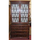 An early 19th century mahogany bookcase over chest, the twin astragal glazed upper doors (some