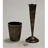 An eastern white metal beaker having an all over repoussee floral decoration, vacant shield shaped