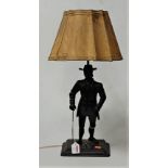 A mid 20th century painted iron figural table lamp, the base in the form of a man in standing pose
