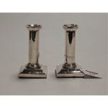 A pair of Victorian dwarf silver table candlesticks, each having plain column to a stepped square