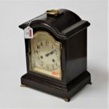 An early 20th century ebonised cased mantel clock, having an arched silvered dial with Arabic