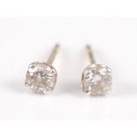 A pair of yellow metal diamond ear studs, each featuring a round brilliant cut diamond in a four