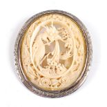 A white metal oval carved ivory brooch, depicting an openwork ivory carving of a Chinese dragon
