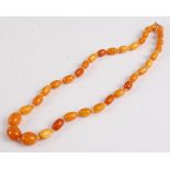 A single row amber necklace, consisting of 35 graduated oval barrel beads strung knotted to a yellow