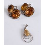 A white metal pear shaped citrine pendant, claw set within a double open surround with a solid bale,