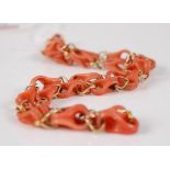 A coral and yellow metal necklace, the carved coral foldover double links each co-joined with yellow