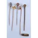 A collection of five yellow metal stick pins, comprising two base metal set with paste stones, one