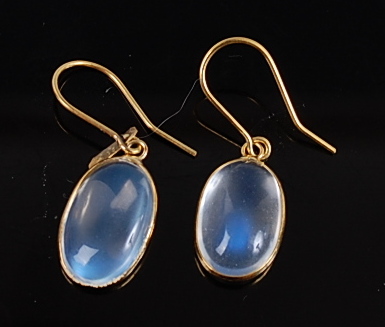 A pair of yellow metal moonstone drop earrings, each featuring an oval cabochon cut moonstone in a