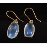 A pair of yellow metal moonstone drop earrings, each featuring an oval cabochon cut moonstone in a