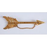 A yellow metal engraved bar brooch in the form of an arrow , with a safety chain, length 105mm,