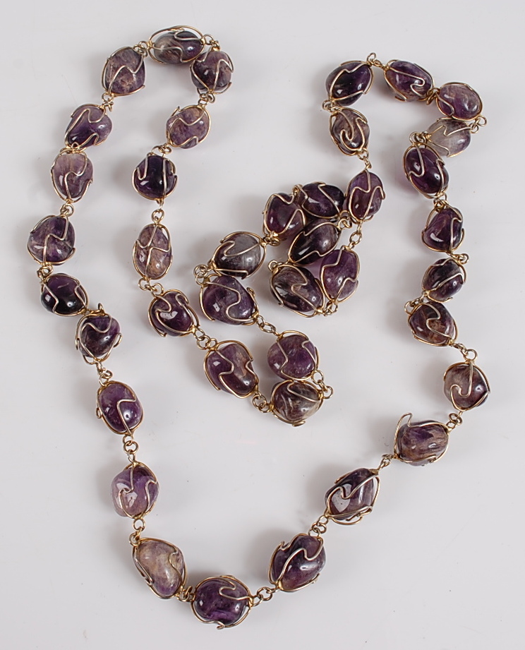 An opera length amethyst necklace, featuring 40 oval amethyst polished stone beads within wire twist