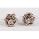 A pair of 9ct white gold diamond ear studs, each arranged as seven small brilliants in a flower head