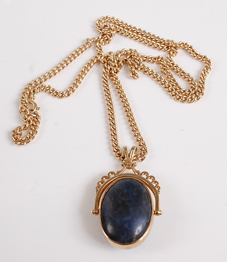 A 9ct yellow gold swivel fob pendant, featuring an oval moss agate cabochon to one side and a blue