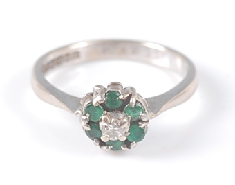 An 18ct white gold, emerald and diamond circular reverse cluster ring, the ring having a centre