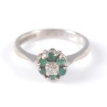 An 18ct white gold, emerald and diamond circular reverse cluster ring, the ring having a centre