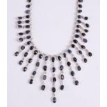 A white metal sapphire fringe necklet , the 99 oval faceted sapphires in bezel settings with a