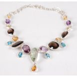 A contemporary silver multi-gem set fringe necklace, having an array of oval and pear cut stones, to