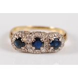 A yellow metal, sapphire and diamond dress ring, arranged as three round cut sapphires, each