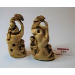 A pair of Japanese okimono, each carved as two figures around a tree trunk, h.9cm