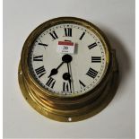 A mid 20th century brass cased ships bulk head clock having a circular enamel dial with Roman