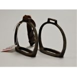 A pair of steel stirrups, one with leather strap