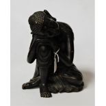 A modern resin figure of a Deity, in seated pose with head resting on his knee, h.29cm