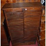 An early 20th century oak twin tambour fronted office filing cabinet, having twin panelled sides,