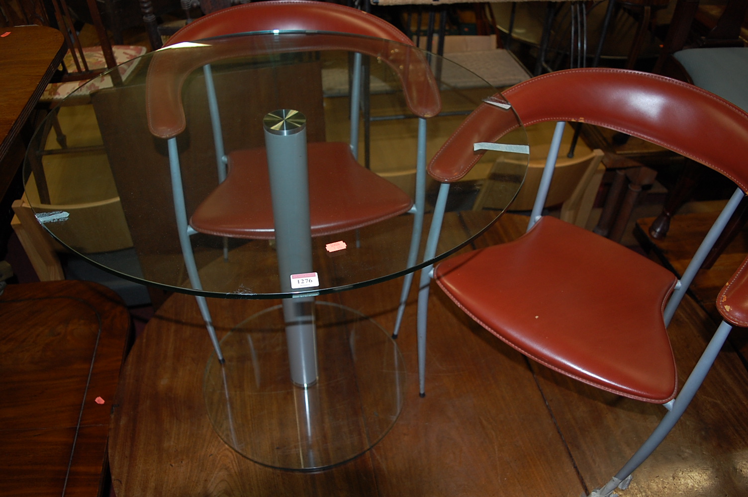 A contemporary circular glass topped and annondised metal pedestal cafe table, together with two