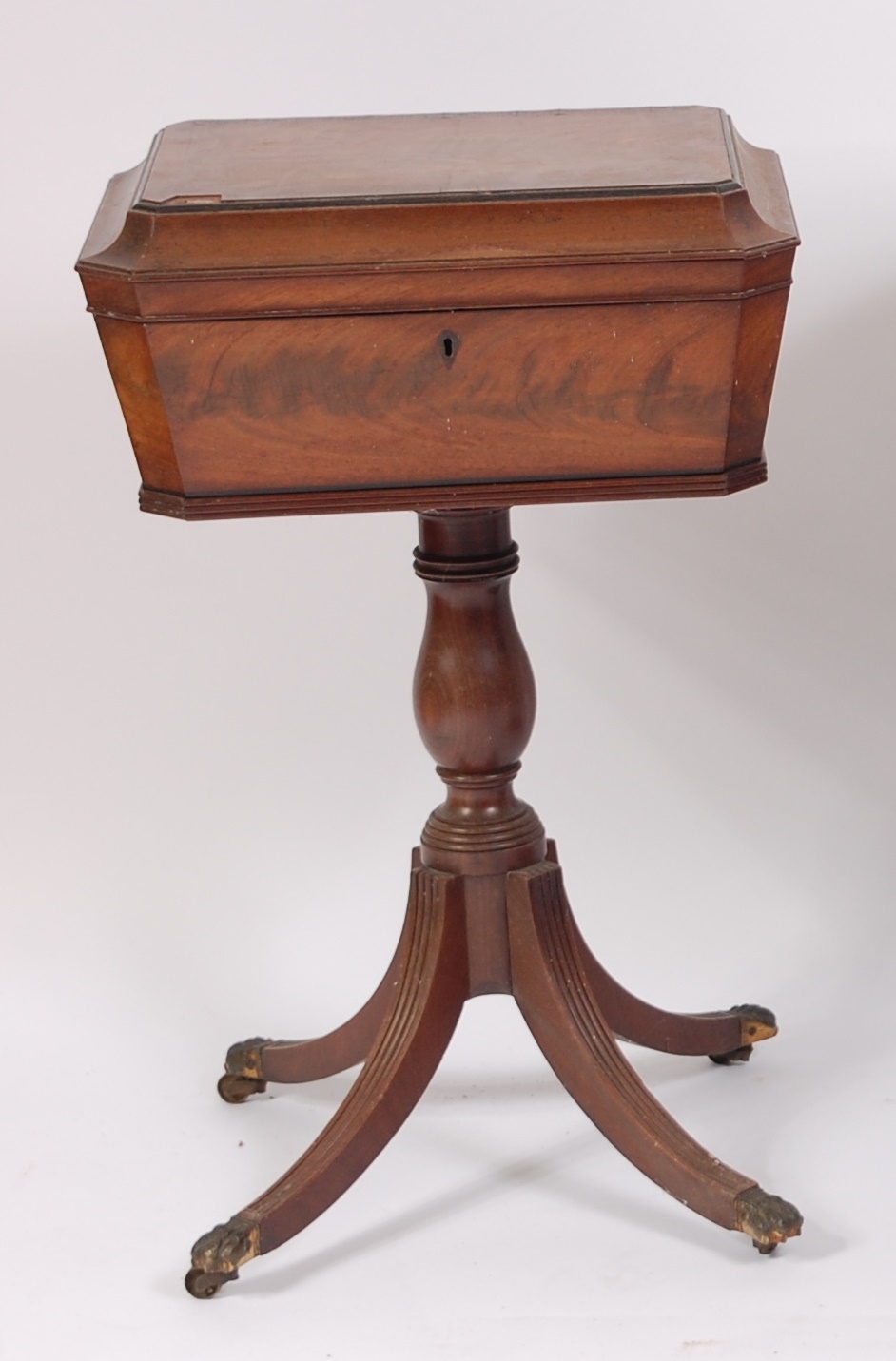 A Regency mahogany pedestal teapoy, the rosewood crossbanded top opening to reveal velvet lined