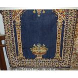 A Persian woollen blue ground rug, the central ground with urn of flowers within columns to trailing